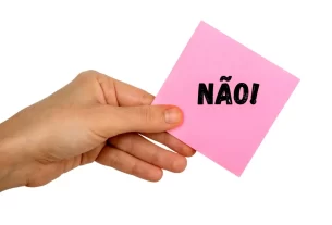 Mão firme segurando uma placa com a palavra 'Não', simbolizando a importância de dizer não e estabelecer limites.