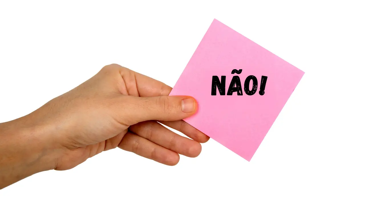 Mão firme segurando uma placa com a palavra 'Não', simbolizando a importância de dizer não e estabelecer limites.