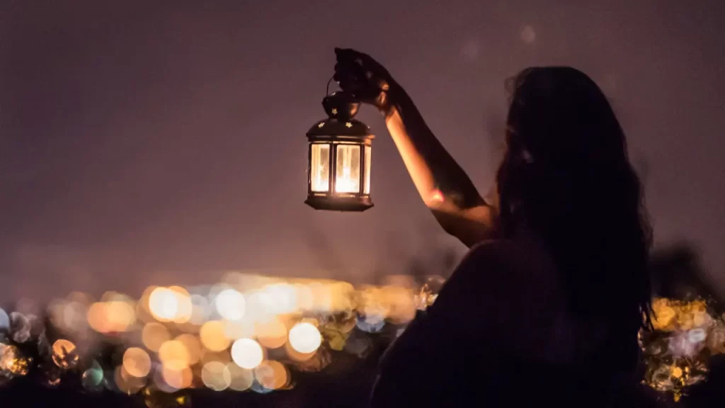 uma mulher segurando uma lamparina em um local escuro para simbolizar que o cristão deve ser sal e luz no mundo, fazendo diferença onde estiver.