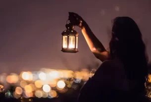 uma mulher segurando uma lamparina em um local escuro para simbolizar que o cristão deve ser sal e luz no mundo, fazendo diferença onde estiver.