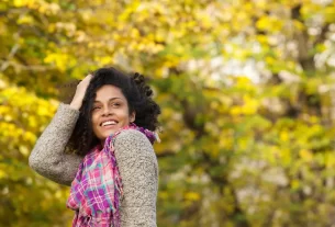 mulher sorrindo ao ar livre, sozinha para demonstrar que é solteira, mas completa em Cristo.