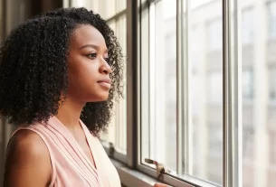 uma mulher olhando pela janela representando mulher ansiosa