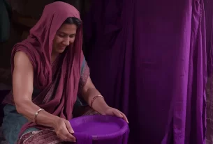 Mulher com tinta tingindo tecido para representar Lídia