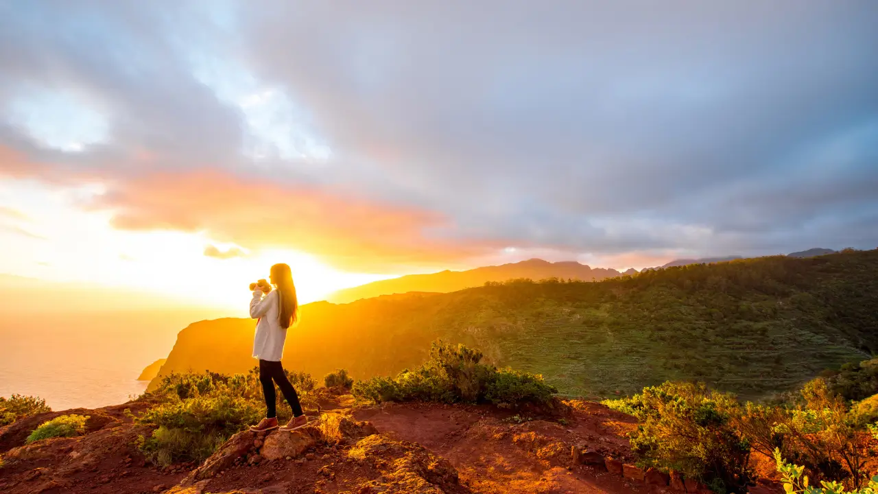 Uma mulher olhando o nascer do sol para simbolizar que a vida é dom de Deus