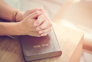 mãos femininas fechadas sobre a Bíblia, simbolizando a mulher que precisa posicionar-se com fé.