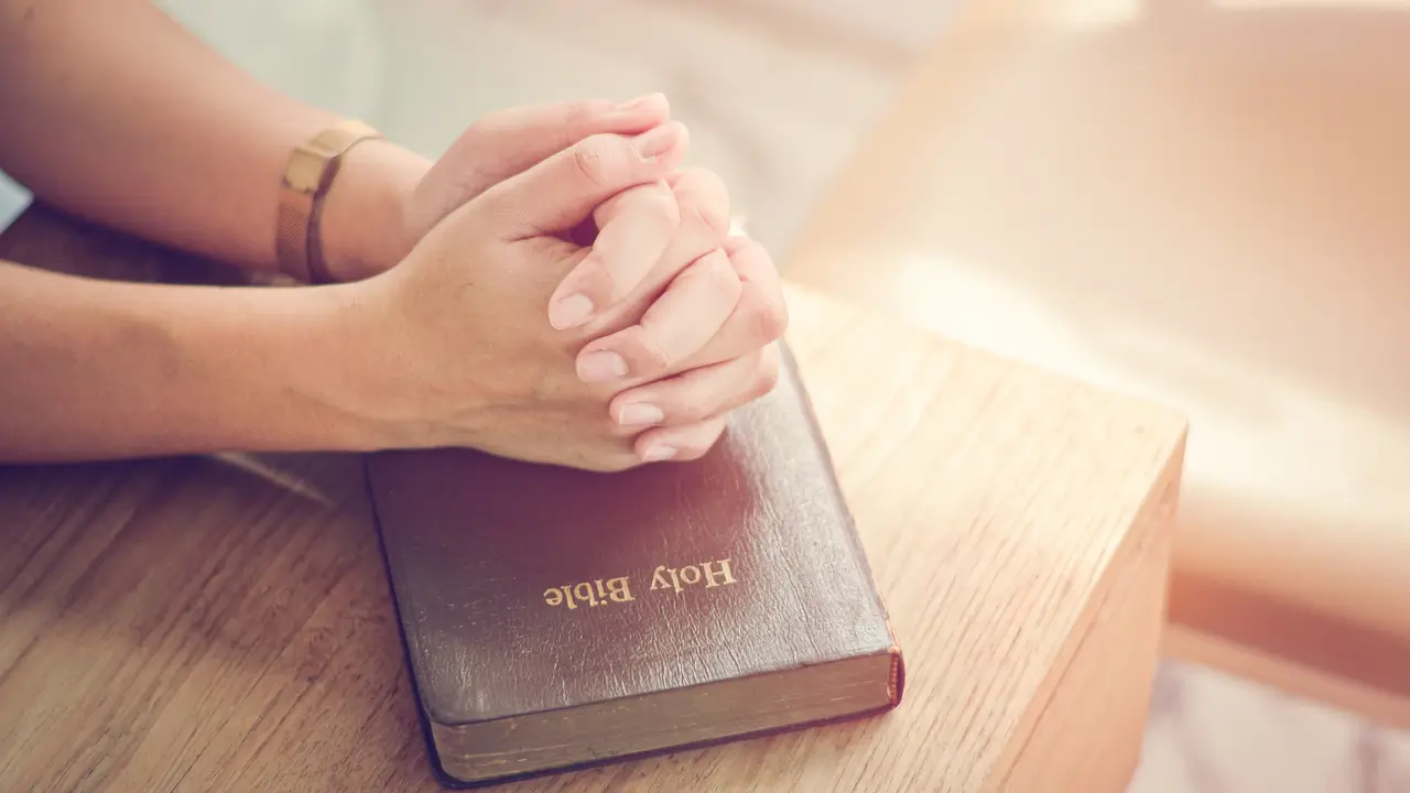 mãos femininas fechadas sobre a Bíblia, simbolizando a mulher que precisa posicionar-se com fé.