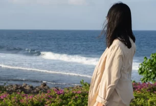 Deus te fortalece representado por uma mulher olhando para o mar