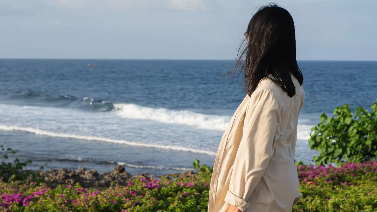 Deus te fortalece representado por uma mulher olhando para o mar