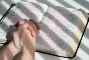 mãos juntas sob a Bíblia para simbolizar oração antes de virar a página do ano