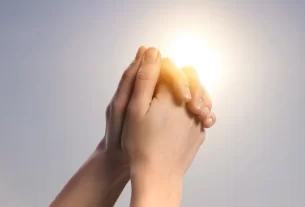 Ana representada por mãos femininas entrelaçadas em forma de oração.