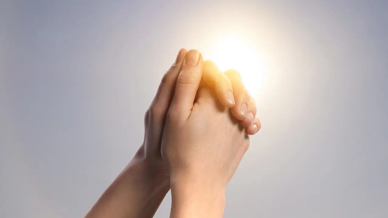 Ana representada por mãos femininas entrelaçadas em forma de oração.