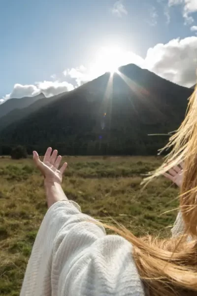 Deus faz novas todas as coisas simbolizado por uma mulher com mãos estendidas no horizonte