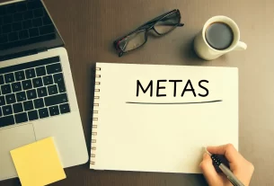 um caderno de anotações em uma mesa e alguém escrevendo a palavra metas espirituais